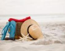 Kapelusz i klapki oparte o plecak na plaży